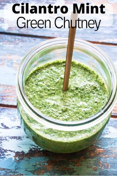 a jar filled with green chutney on top of a wooden table