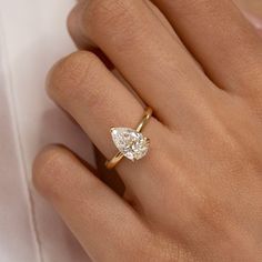 a woman's hand with a diamond ring on top of her finger and the other hand holding an engagement ring