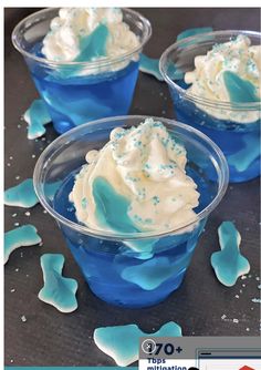 three cups filled with blue jello and whipped cream