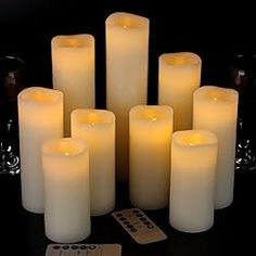 a group of white candles sitting next to each other on top of a black table