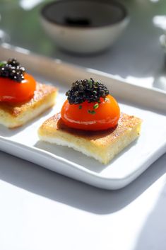 two pieces of bread with tomatoes and black cavia on them sitting on a white plate