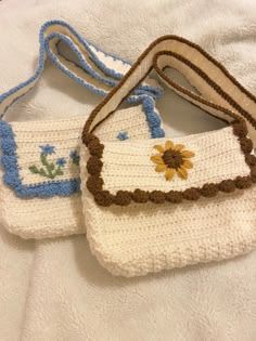 two crocheted purses sitting on top of a white bed next to each other