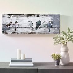 three birds sitting on a wire in front of a vase with flowers and two candles