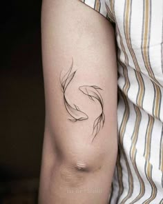 a woman's arm with a small fish tattoo on the left side of her arm