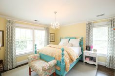 a bedroom with yellow walls and blue bedding in the center, along with a chandelier hanging from the ceiling