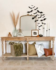 a wooden table topped with lots of pillows next to a mirror and vase filled with plants