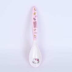 a pink hello kitty toothbrush sitting on top of a white spoon with the word hello kitty written on it