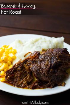 a white plate topped with meat, potatoes and mashed potatoes on top of a wooden table