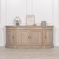 a wooden sideboard sitting on top of a hard wood floor next to a lamp