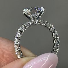 a close up of a person's hand holding an engagement ring