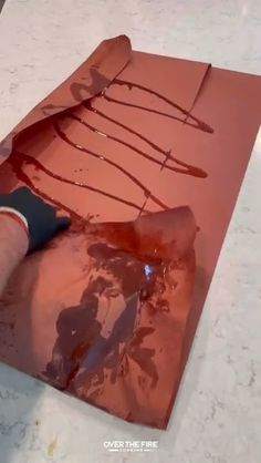 someone is painting a piece of paper with red paint