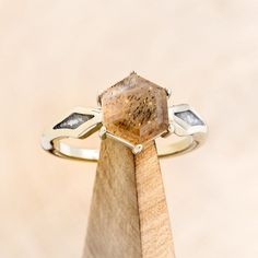 a ring that is sitting on top of a piece of wood and has a stone in it