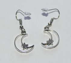 "Crescent moon star earrings. Antique silver tone crescent moon and star charms dangling from hypoallergenic steel hooks with rubber backs. Earring length: 37mm, 1.5\" Charm material: zinc alloy, lead free cadmium free This listing is for one pair of mon and star earrings with rubber backs. This earring will come in a gift bag. I offer combined shipping costs which give you a shipping discount for ordering multiple items from my shop. Earrings care: Take them off while you sleep, sports activiti Cheap Dangle Earrings With Moon Charm, Silver Crescent Earrings With Star Charm, Celestial Silver Hoop Earrings Hypoallergenic, Silver Stainless Steel Earrings With Star Charm, Crescent Silver Metal Earrings, Hypoallergenic Adjustable Star Earrings, Adjustable Silver Celestial Hoop Earrings, Metal Moon Charm Earrings In Celestial Style, Silver Star Charm Earrings In Stainless Steel