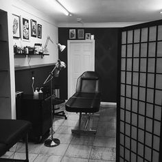 a black and white photo of a chair in a room with pictures on the wall