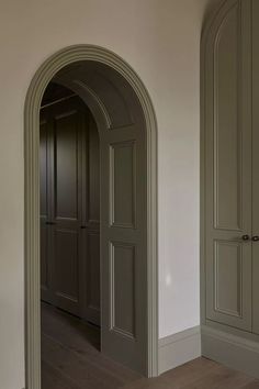 an archway leading to another room with wood flooring and gray painted doors in it