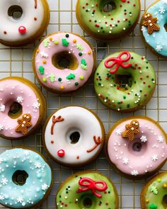 twelve donuts with different colored frosting and sprinkles on a cooling rack