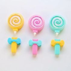 four lollipops in different colors and shapes on a white surface, one with a bow tie