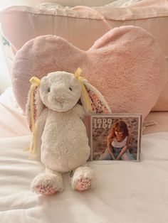 a stuffed animal sitting on top of a bed next to a photo frame and pillow