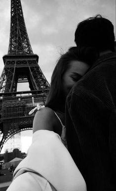 a man and woman hugging in front of the eiffel tower