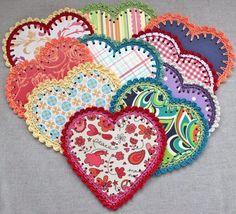 six heart shaped doilys are laid out on a gray tablecloth with different patterns and colors