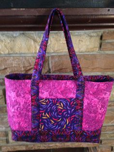 a pink and purple bag hanging from a brick wall