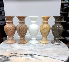 five vases are lined up on a marble table