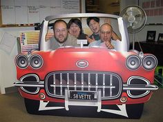 three men are sitting in the back of a red car