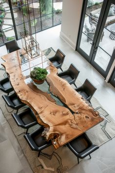 a dining room table made out of wood with chairs around it and a plant in the center