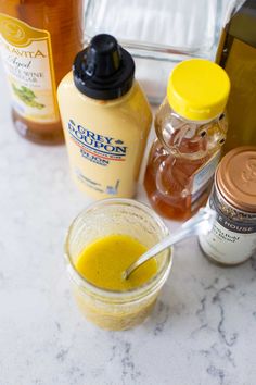 the ingredients to make an orange juice smoothie sit on a marble countertop next to bottles of honey