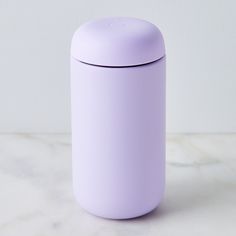 a purple canister sitting on top of a white marble counter next to a wall