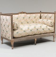 an antique couch with floral upholstered fabric and wood frame, in the shape of a sofa