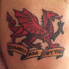 a close up of a person's leg with a tattoo on it that has a dragon and banner