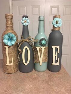 three wine bottles decorated with flowers and the word love