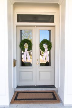 two wreaths on the front door of a house