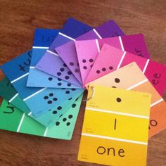 colorful cards with numbers and letters on them sitting on top of a wooden table in front of a pair of scissors