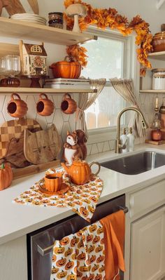 a kitchen filled with lots of pumpkins and dishes on top of a counter next to a sink