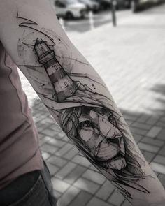 a man's arm with a lighthouse and lion tattoo on it