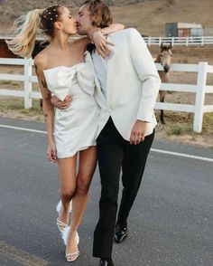 a man and woman are walking down the street with their arms around each other as they kiss