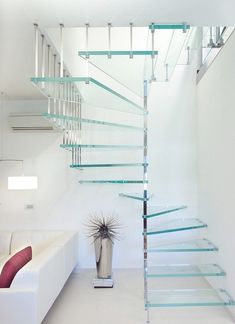 a living room with a white couch and glass stair case in the middle of it