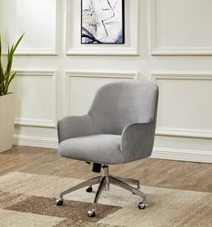 a gray office chair sitting on top of a wooden floor next to a potted plant