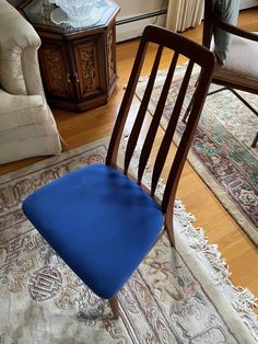 a blue chair sitting on top of a wooden floor next to a rug and table