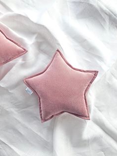 two pink stars are laying on a white sheet