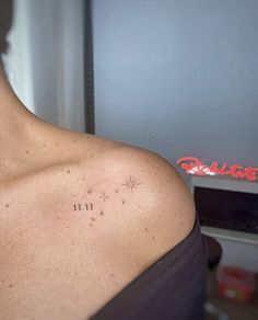 the back of a woman's shoulder with small tattoos on her left arm and chest