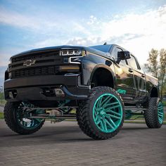 a black truck with turquoise rims parked on the street