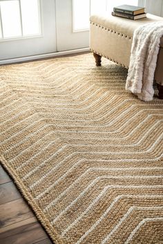 a large rug in the corner of a room with a bench and window behind it