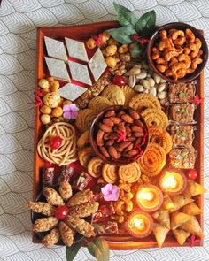 a tray filled with lots of different types of food and candles on top of it