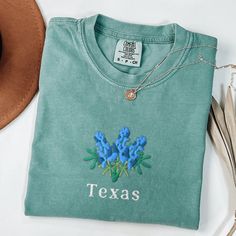 Comfort Colors Embroidered Shirt, Texas Bluebonnets Shirt, Embroidered Texas Shirt, Texas Crewneck, Embroidered Bluebonnets Shirt This embroidered bluebonnets comfort colors shirt is everything. Perfect to wear in the springtime! *If you order a white shirt I will automatically change the text color to navy unless unless otherwise stated in the personalization section* Please let me know if you are interested in a size 4X, I have certain size and color options available! ✨ 100% Cotton ✨ Pre-shrunk ✨ Relaxed fit Care: Machine wash: warm (max 40C or 105F) Tumble dry: low Do not iron directly on the print REFUNDS AND EXCHANGES All items are made to order using multiple suppliers to ensure quick worldwide shipping. For this reason we are unable to accept returns/exchanges unless there's a defe Green Spring Tops With Embroidered Logo, Spring Green Tops With Embroidered Logo, Green Spring Top With Embroidered Logo, Spring Green Top With Embroidered Logo, Blue T-shirt With Embroidered Text For Spring, Blue Tops With Embroidered Logo For Spring, Blue Tops With Embroidered Text For Spring, Blue Tops With Custom Embroidery For Spring, Casual Spring Shirt With Custom Embroidery