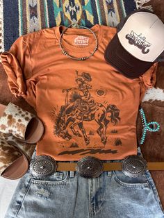 Channel your inner cowgirl with this bold and empowering tee. Featuring a striking rider graphic, it's perfect for those who embrace their wild side. Unisex fit  Made in the USA Classic Cowgirl, Cowgirl Design, Cowgirl Clothes, Camping Aesthetic, Womens Jumpsuits, Country Clothing, Buy List, Cowgirl Shirts, Country Charm