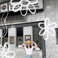 a woman standing in front of a building with flowers on her head and an advertisement above the door