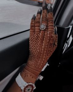 a woman's hand with henna on it sitting in the passenger seat of a car